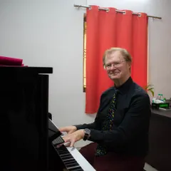 A portrait of the ABRSM examiner, Mr. Richard Lewis, at the piano during the exams at our school.