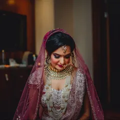 A portrait of a bride looking serene and beautiful on her wedding day. Her intricate jewelry and stunning lehenga are perfectly complemented by her calm demeanor.