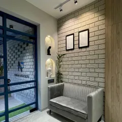 The entrance and waiting area of our studio. We used an exposed brick wall, a comfortable velvet sofa, and arched niches to create a warm and welcoming first impression for our clients.