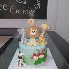 A delightful jungle safari cake for a first birthday. This design includes a lion, elephant, giraffe, zebra, and monkey, all handcrafted from fondant.