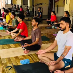 A class of students sits in meditation, turning their focus inward. This practice of stillness is essential for any aspiring yoga teacher.