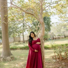 A beautiful smile from a mama-to-be, feeling radiant and joyful in her flowing red gown during this garden maternity shoot.