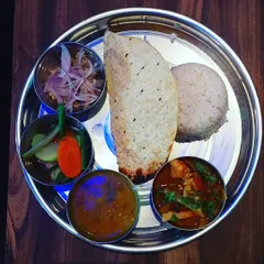 A closer look at our Naga special thali served in traditional steel plates. You get rice, dal, a main curry, a side of eromba, pickles, and a papad for that extra crunch.