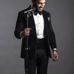 The same velvet tuxedo, captured in a moment of performance. The richness of the velvet and the sharp lines of the tailoring create an unforgettable stage presence.