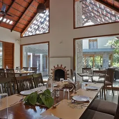 The dining area of this nature resort features high, tiled roofs and large, open windows. This design maximizes natural light and ventilation, allowing diners to feel connected to the beautiful estate grounds outside.