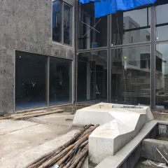 A "before" shot of a courtyard during construction, with bare concrete and scaffolding. This image provides a stark contrast to the finished landscape, highlighting the transformative power of design.