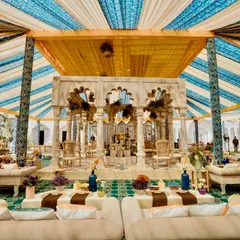 The central bar and pavilion of the 'Rang Mahal' event, featuring intricately carved stone columns and arches. The design blends traditional Rajasthani architecture with a fresh, celebratory color palette.