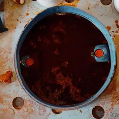 This is where color comes to life. An abstract, top-down shot of a dye vat, capturing the deep, rich hue and the raw, industrial start of a color story for a textile brand.