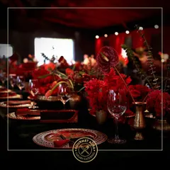A bold and dramatic table setting with vibrant red floral arrangements and intricate plates. We tailor our presentation to match any theme, no matter how daring.