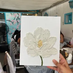 A finished piece from one of our recent texture art workshops. The simple, elegant white flower with a golden center is a popular design that participants love to create and take home.
