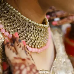 A detailed shot of the bride's stunning kundan necklace and mehendi-adorned hands, highlighting the beauty of her bridal jewelry.