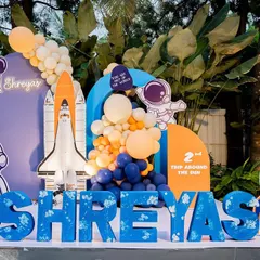 A detailed view of the space party backdrop, with custom "SHREYAS" lettering, astronaut props, and a model of the space shuttle.