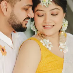 A sweet moment from Samridhi's Haldi. Her makeup was kept very natural and dewy, complemented by beautiful floral jewelry for that perfect, fresh Haldi look.
