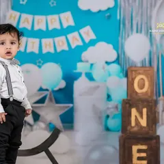 A handsome little man celebrating his first birthday. The 'Happy Birthday' banner and 'ONE' blocks create a perfect backdrop for this milestone photo.