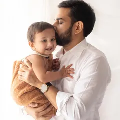 A father's loving kiss for his smiling baby. This bright and simple portrait is a beautiful example of capturing a tender dad and child moment.