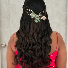 A romantic half-up, half-down hairstyle with soft waves. The look is completed with a delicate, nature-inspired hair accessory.