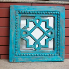 Here is the square carved mirror in a bold turquoise finish, shown against a rustic brick background. This view highlights how the vibrant color and distressed texture can add an unexpected and artistic element to your indoor or outdoor living spaces.