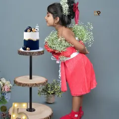Making a wish! This charming photo captures a little girl celebrating her fifth birthday. The setup includes a beautiful cake, wooden stands, and a light-up number five for a festive touch.