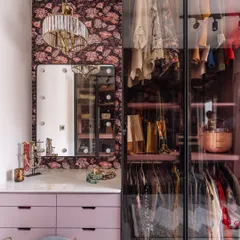 This chic walk-in closet is a dream come true, featuring custom lilac cabinetry, a vanity with Hollywood-style lighting, and glass-front wardrobes. We designed this space to be both a functional dressing room and a personal style sanctuary.