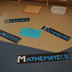 Our learning environment is set up to introduce foundational concepts. Here, floor labels for Science, Technology, Engineering, and Mathematics (STEM) define different play zones.