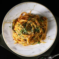 An overhead view of our perfectly plated Aglio Olio Spaghetti. The simplicity of the dish allows the quality of the fresh pasta and fragrant garlic and herbs to shine through.