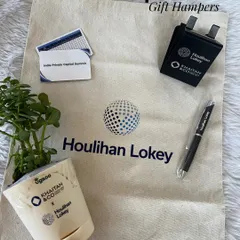 The complete corporate gift hamper for Houlihan Lokey. It includes a branded tote bag, a plant, a pen, a charger, and an event card, creating a useful and memorable giveaway.