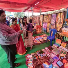 Customers browsing my collection of paintings and crafts at Chitra Santhe. I love seeing people connect with my art in person.
