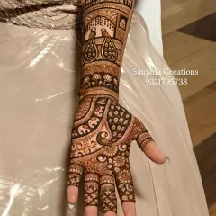 A full-length view of a personalized bridal design. We incorporated a bride and groom figure, palace architecture, and peacocks to create a complete story on her arms.
