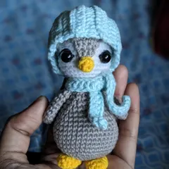 This little penguin is all bundled up with a light blue hat and a matching scarf.