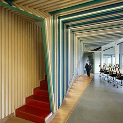 The 'red' stairwell in the Kadence Office is a bold, hollowed-out element that connects the two floors. It acts as a vibrant focal point, a streak of color that cuts through the space and guides movement.