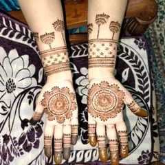 This design features a detailed mandala on the palm and unique, stylized tree or flower motifs on the wrist. It's a creative and modern take on party henna.