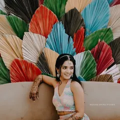 A modern and vibrant Mehendi or Haldi backdrop made of large, multi-colored dried palm leaves, creating a unique and artistic photo corner.