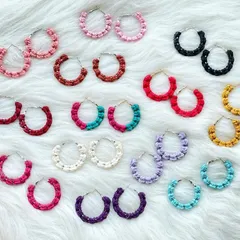 My collection of macrame hoop earrings, available in a wide spectrum of colors. This image displays pairs in shades of pink, red, black, yellow, purple, and blue, showing how these lightweight knotted hoops can add a simple yet colorful statement to your look.