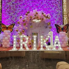 For Irika's first birthday, I created this grand stage with large, illuminated marquee letters spelling out her name. The backdrop is a full flower wall, complemented by a pink balloon arch and butterfly accents.