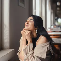A serene moment from the 'Bonsoir' series. The off-shoulder styling of the trench coat and delicate pearl earrings create a soft, romantic, and fashionable look.