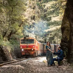 The iconic Shimla toy train passes by as the couple shares a quiet moment, blending history and romance. This shot captures the timeless charm of a classic Himalayan pre-wedding photoshoot.
