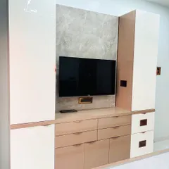 I designed this bedroom TV unit with a mix of high-gloss white and beige laminates for a subtle, elegant look. The unit provides a combination of drawers and cabinets for extensive storage.