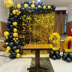 A bold and glamorous setup for a 30th birthday. The gold sequin wall provides a stunning photo backdrop, framed by a black and gold balloon garland and large foil numbers.