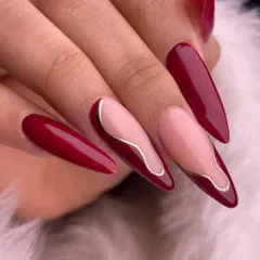 A powerful and elegant design in deep red. This set features a mix of solid color and negative space nails with delicate gold line art, creating a look that is both bold and sophisticated on long stiletto extensions.