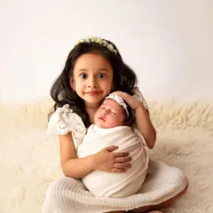 Look at that proud big sister. I gently guide siblings to interact with the baby in a way that is safe and natural, capturing their genuine excitement and love.