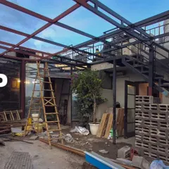 The same terrace "during" construction, with the new metal framework for a pergola being installed, showing the structural transformation in progress.