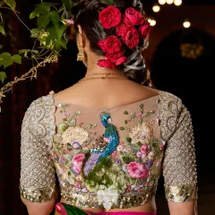 This is the Nemali Vanam blouse, a piece that captures the poetry of a peacock's dance. The back is set against a sheer base, allowing the intricate hand embroidery of lush florals and a regal peacock to become the centerpiece. The sleeves are embellished with katdana detailing, echoing the artistry of temple architecture.