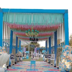 A grand entrance tunnel for an outdoor carnival party. The walkway is decorated with colorful ceiling drapes, chandeliers, and a custom printed floor.