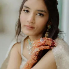 A close-up of Moksha's natural beauty. The makeup is minimal and soft, enhancing her features and letting her stunning jewelry and henna stand out.