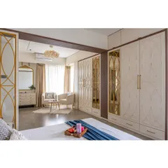 A full view of the custom floor-to-ceiling wardrobes with intricate gold and mirror detailing. This design provides ample storage while serving as a stunning feature wall.