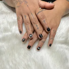 Not your basic black manicure. This unisex set on short nails features a mix of hand-painted geometric patterns, including grids, stripes, and an evil eye design for an edgy, punk-inspired look.