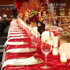 A regal, long-table dining arrangement in vibrant red, set with golden candelabras and glassware. This setup exemplifies our flair for creating dramatic and luxurious atmospheres for grand celebrations.