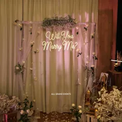 A full view of our indoor proposal decoration package. We use a stand with sheer curtains, fairy lights, and floral arrangements to create a dedicated, photo-ready spot within any room.