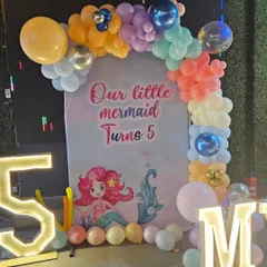 The main backdrop for the mermaid party, featuring a beautiful balloon arch and a personalized "Our little mermaid Turns 5" banner.