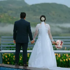 A quiet moment for the couple, holding hands as they look out at the misty mountains. This scenic wedding shot creates a sense of peace and togetherness.